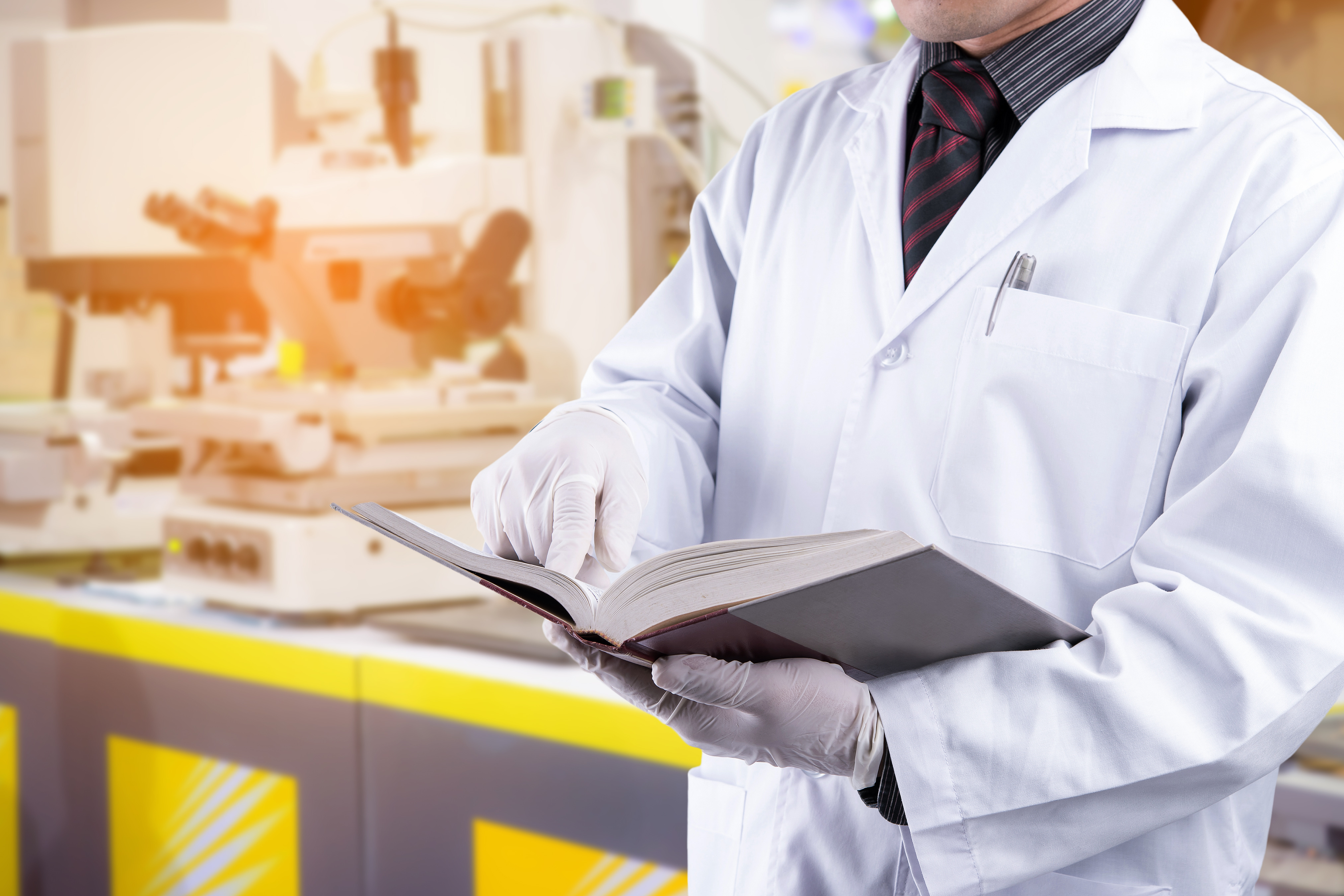 Scientist reading textbook with laboratory background